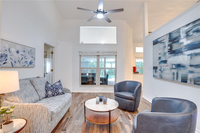 living room with a high ceiling, hardwood / wood-style flooring, and ceiling fan