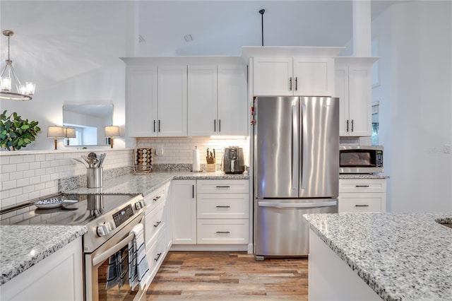 kitchen featuring light stone countertops, appliances with stainless steel finishes, backsplash, pendant lighting, and white cabinetry