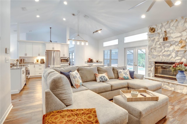 living room featuring ceiling fan, light hardwood / wood-style floors, high vaulted ceiling, and french doors