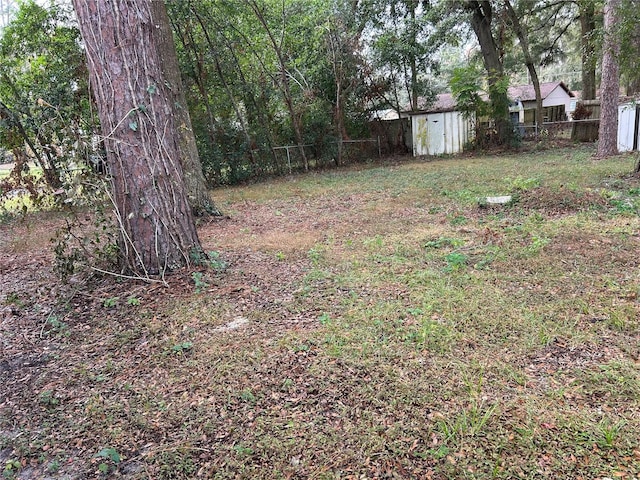 view of yard with an outbuilding, fence, and a storage shed