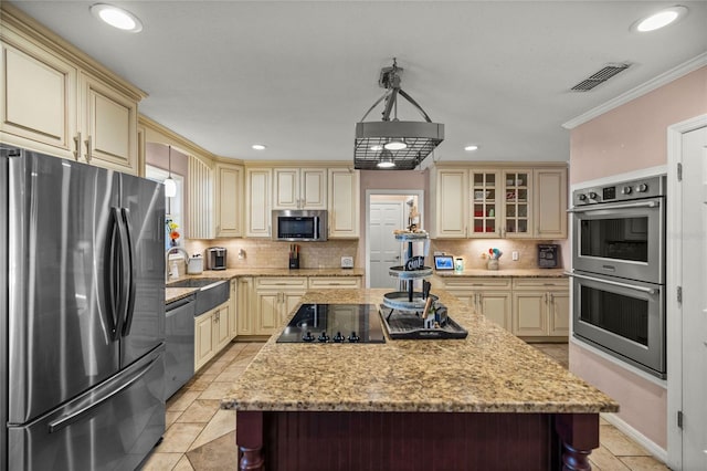 kitchen with appliances with stainless steel finishes, hanging light fixtures, ornamental molding, a kitchen island, and backsplash