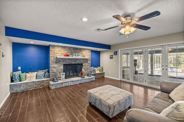 living room with french doors, a fireplace, ceiling fan, and a textured ceiling