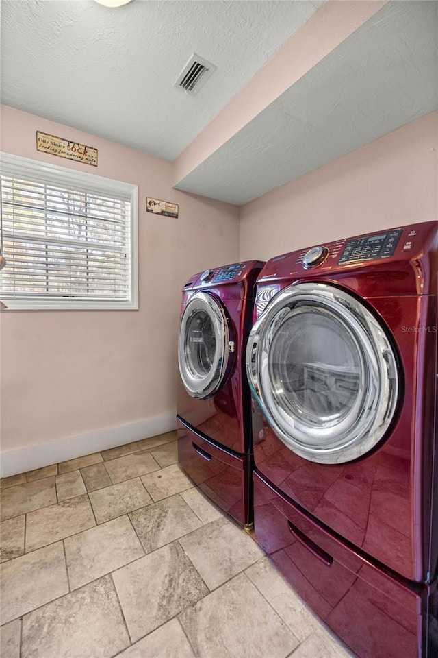 laundry room featuring a textured ceiling and washing machine and dryer