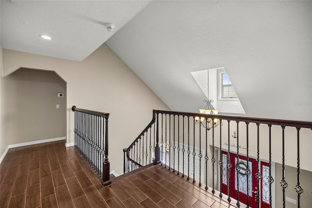 stairs with a textured ceiling, a chandelier, and vaulted ceiling