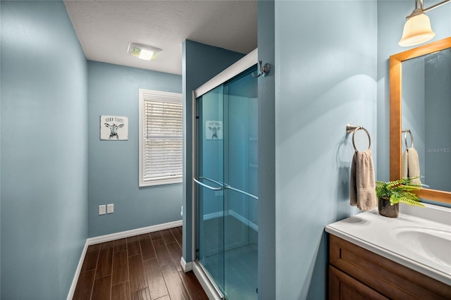 bathroom featuring a shower with door, vanity, and a textured ceiling