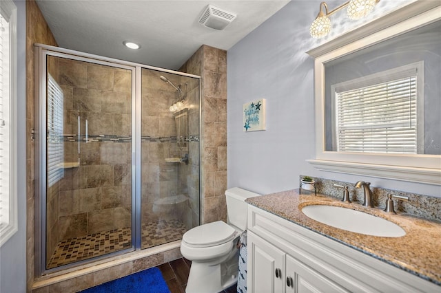 bathroom with vanity, a shower with shower door, and toilet