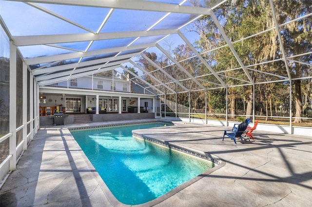 view of swimming pool featuring glass enclosure and a patio