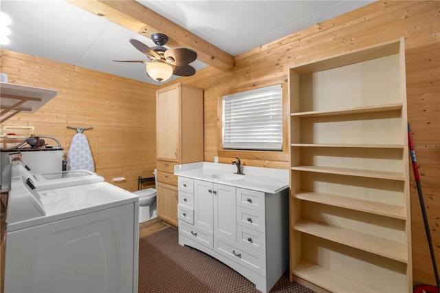 clothes washing area with ceiling fan, wood walls, sink, and washing machine and clothes dryer