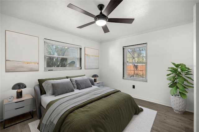 bedroom with dark hardwood / wood-style floors, ceiling fan, and ornamental molding