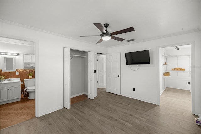 unfurnished bedroom with ensuite bath, ceiling fan, crown molding, and hardwood / wood-style flooring