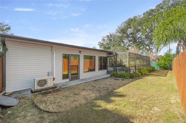 rear view of house featuring glass enclosure, a yard, and ac unit