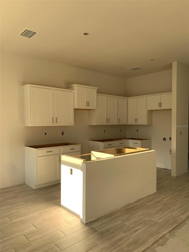 320 W Rexford Dr, Beverly Hills, FL 34465 - kitchen with a center island, visible vents, white cabinetry, and light wood-style flooring