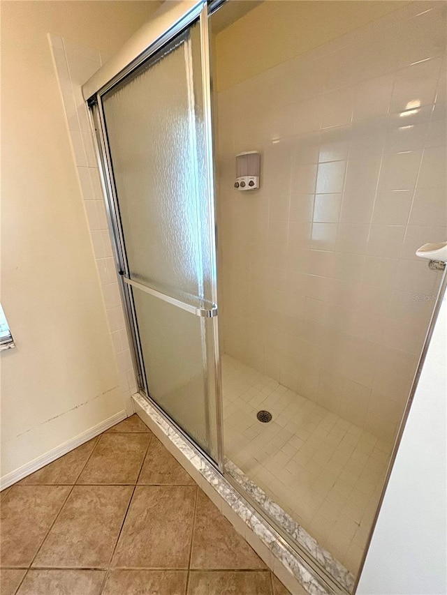 bathroom with a shower with door and tile patterned floors