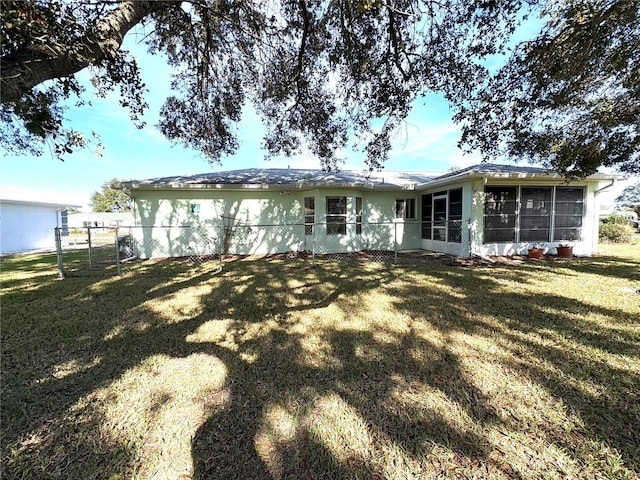 back of property with a sunroom and a yard