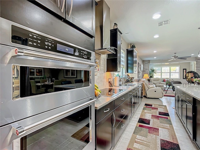 kitchen featuring ceiling fan, black electric cooktop, stainless steel double oven, sink, and backsplash