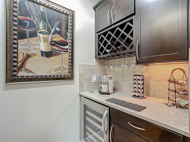 bar with beverage cooler, dark brown cabinets, and decorative backsplash