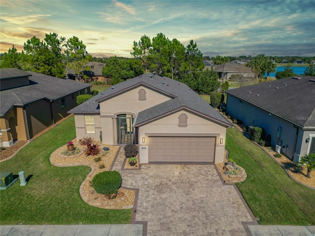 ranch-style house featuring a water view, a garage, and a lawn