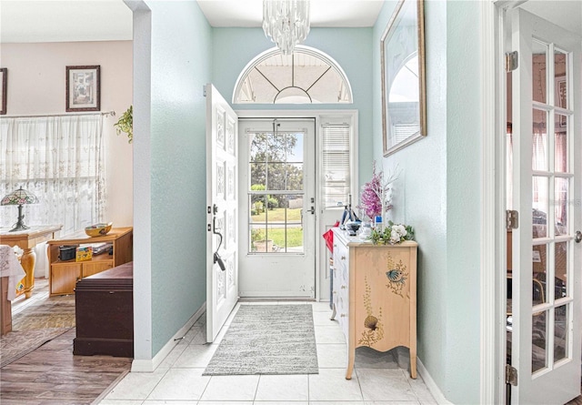 foyer entrance with light tile patterned flooring and an inviting chandelier