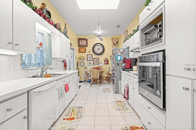 kitchen featuring white cabinets, sink, ceiling fan, light tile patterned floors, and appliances with stainless steel finishes