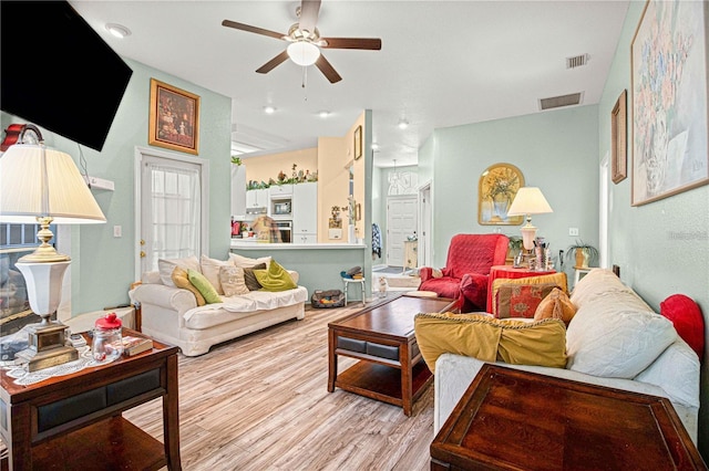 living room with light hardwood / wood-style floors and ceiling fan