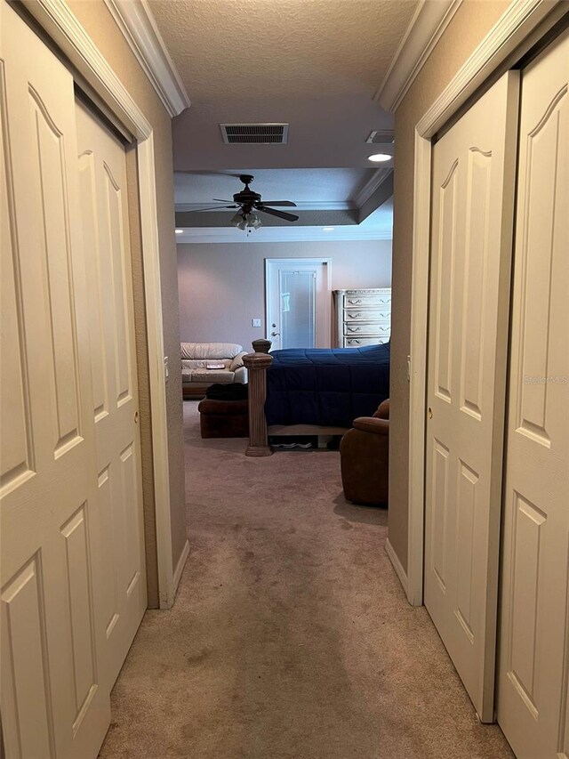 corridor featuring a textured ceiling, light colored carpet, and crown molding