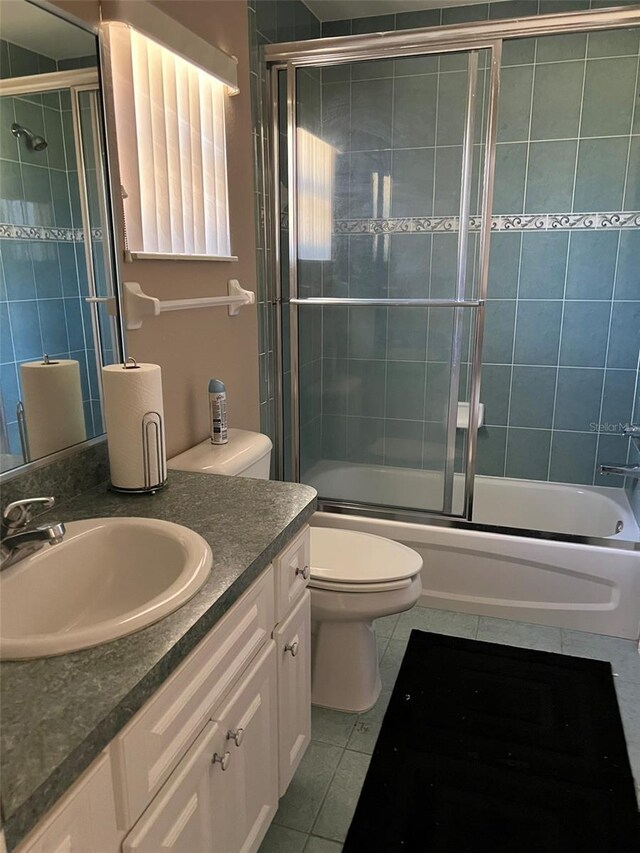 full bathroom featuring tile patterned flooring, vanity, bath / shower combo with glass door, and toilet