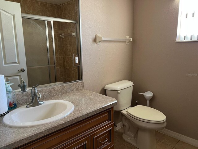 bathroom with toilet, vanity, tile patterned floors, and an enclosed shower