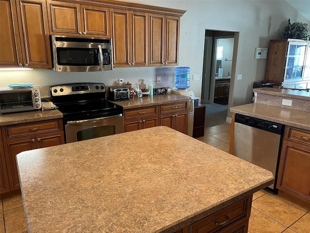 kitchen with appliances with stainless steel finishes, a center island, and light tile patterned flooring