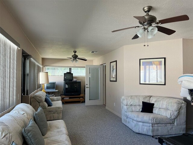 carpeted living room featuring ceiling fan and a textured ceiling