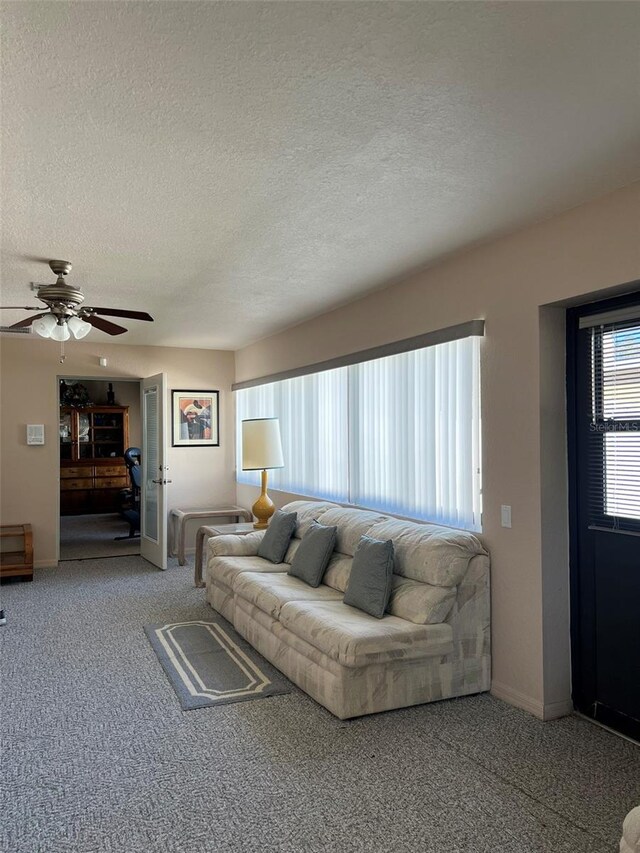 carpeted living room featuring ceiling fan and a textured ceiling