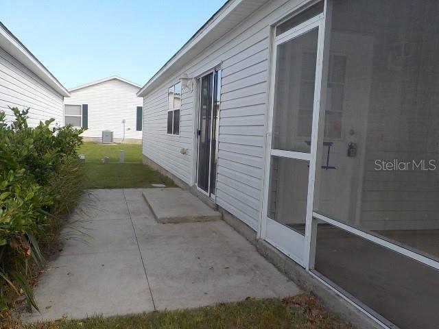 view of side of home with a lawn, central AC, a patio area, and a sunroom