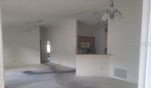 unfurnished living room with ceiling fan with notable chandelier