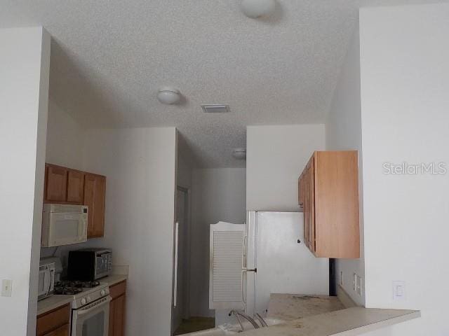 kitchen with a textured ceiling and white appliances