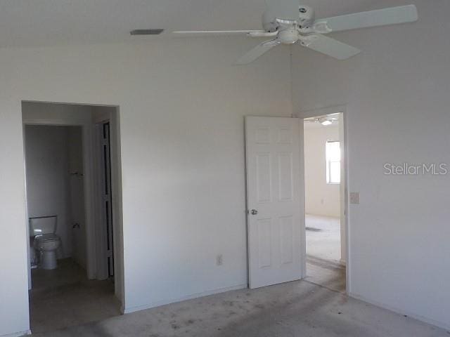 unfurnished bedroom featuring light colored carpet, ensuite bath, ceiling fan, and lofted ceiling