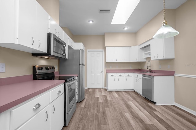 kitchen featuring white cabinets, decorative light fixtures, stainless steel appliances, and sink