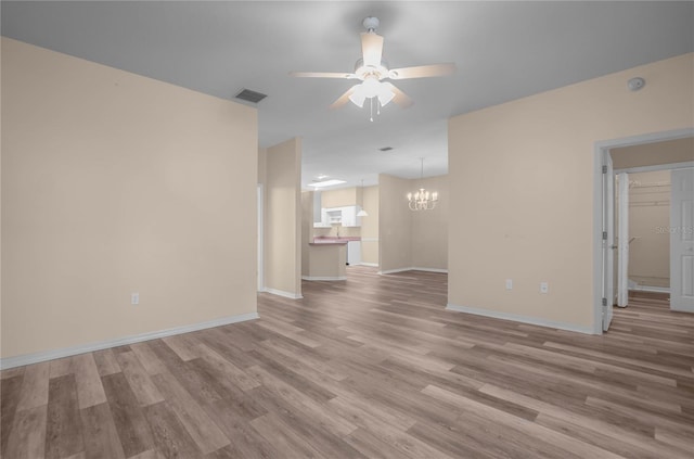 unfurnished living room featuring ceiling fan with notable chandelier and light wood-type flooring