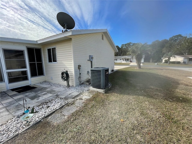 view of side of home with a yard, cooling unit, and a patio