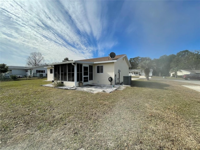 rear view of house with a lawn, a patio area, a sunroom, and central AC unit