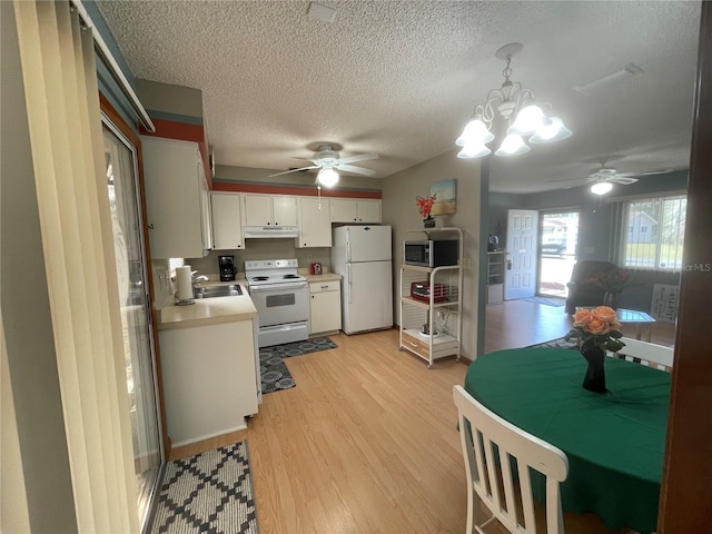 kitchen featuring white appliances, sink, light wood-type flooring, decorative light fixtures, and white cabinetry