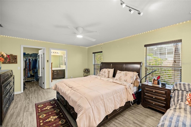 bedroom featuring light hardwood / wood-style flooring, ceiling fan, a spacious closet, connected bathroom, and a closet