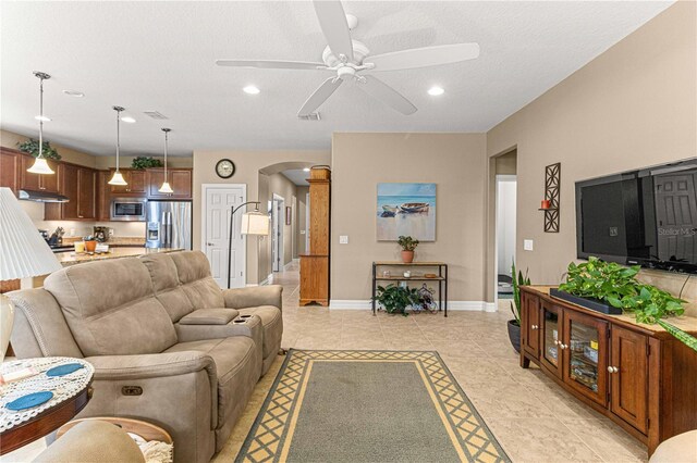 tiled living room featuring ceiling fan and a textured ceiling