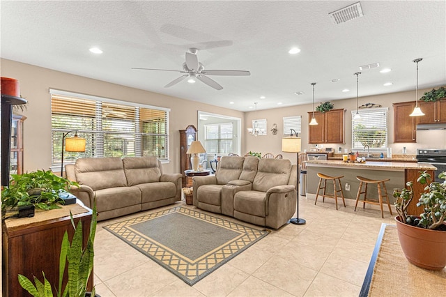 living room featuring ceiling fan, sink, light tile patterned floors, and a textured ceiling