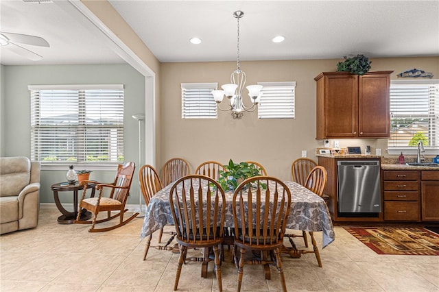 tiled dining area featuring ceiling fan with notable chandelier, a healthy amount of sunlight, and sink