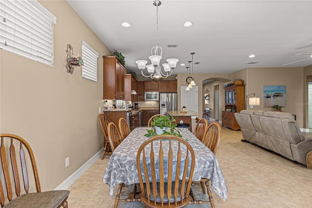 tiled dining room featuring ceiling fan with notable chandelier