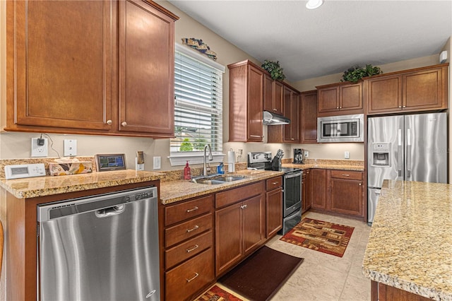 kitchen with appliances with stainless steel finishes, light stone counters, and sink