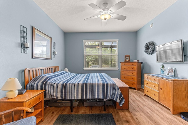 bedroom with ceiling fan, a textured ceiling, and light hardwood / wood-style flooring