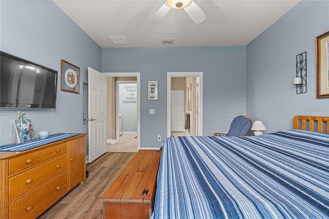 bedroom featuring a textured ceiling, ensuite bathroom, ceiling fan, and light hardwood / wood-style floors