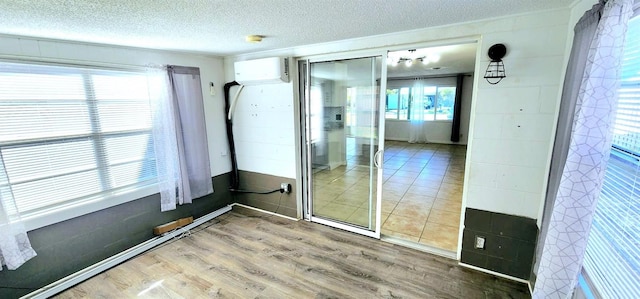 bathroom featuring an AC wall unit, plenty of natural light, hardwood / wood-style floors, and a textured ceiling