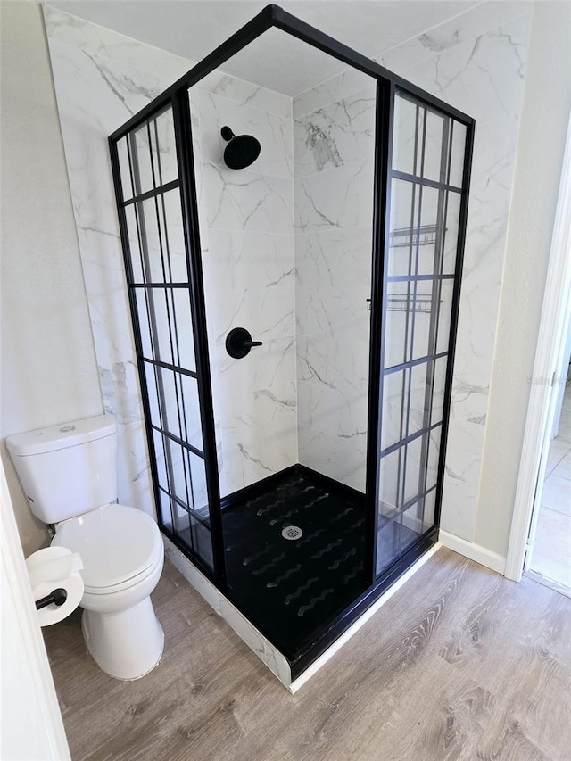 bathroom with tiled shower, hardwood / wood-style flooring, and toilet