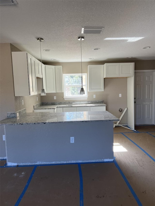 kitchen featuring white cabinets, decorative light fixtures, and light stone countertops